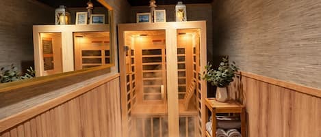 Una sala de sauna con paredes de madera, un banco, un estante con toallas y un espejo.