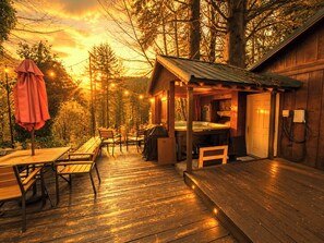 Une cabane en bois dotée d’un bain à remous, d’un espace salon extérieur et d’une terrasse.