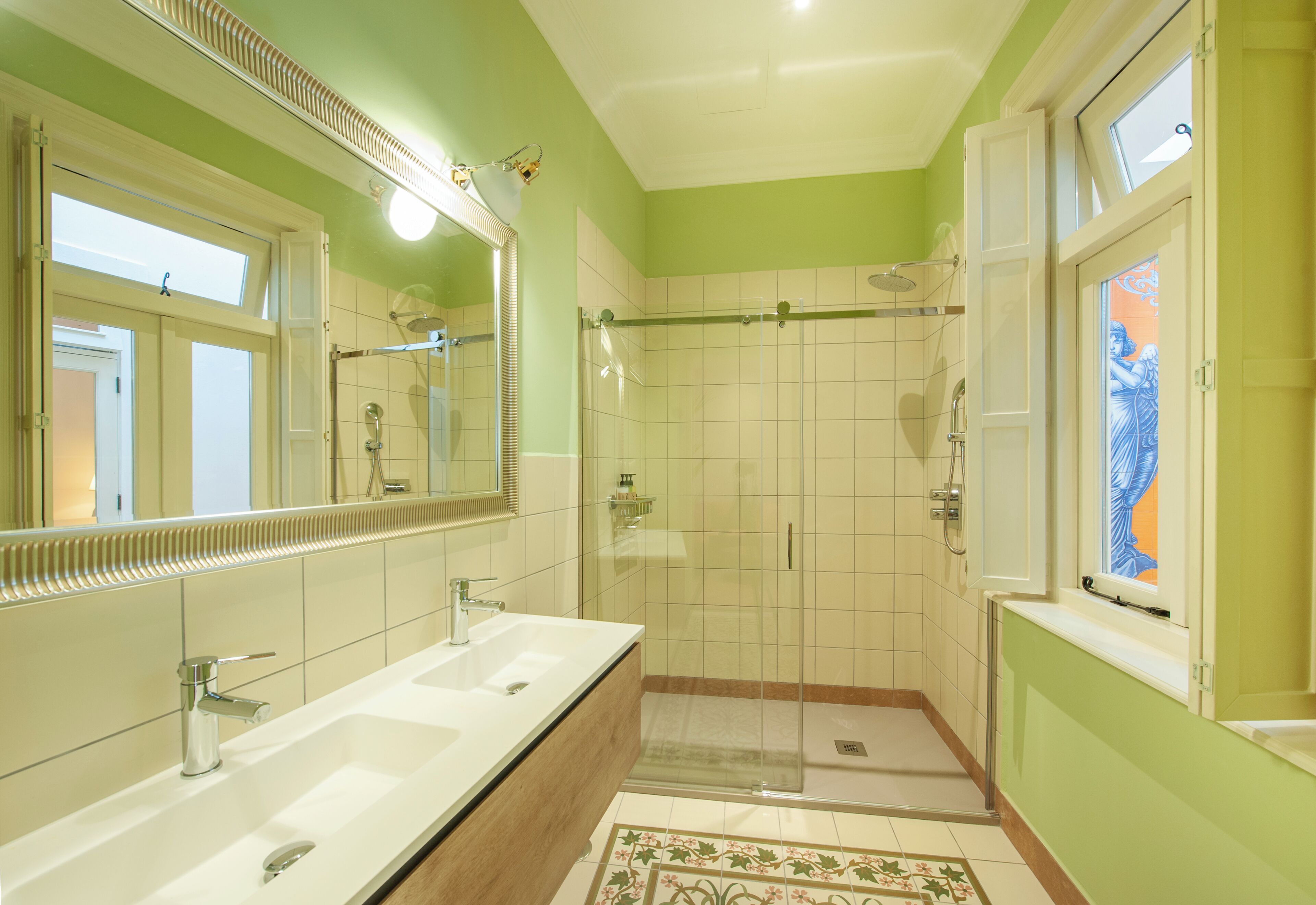 Une salle de bain avec deux lavabos, une douche à parois de verre et un grand miroir.