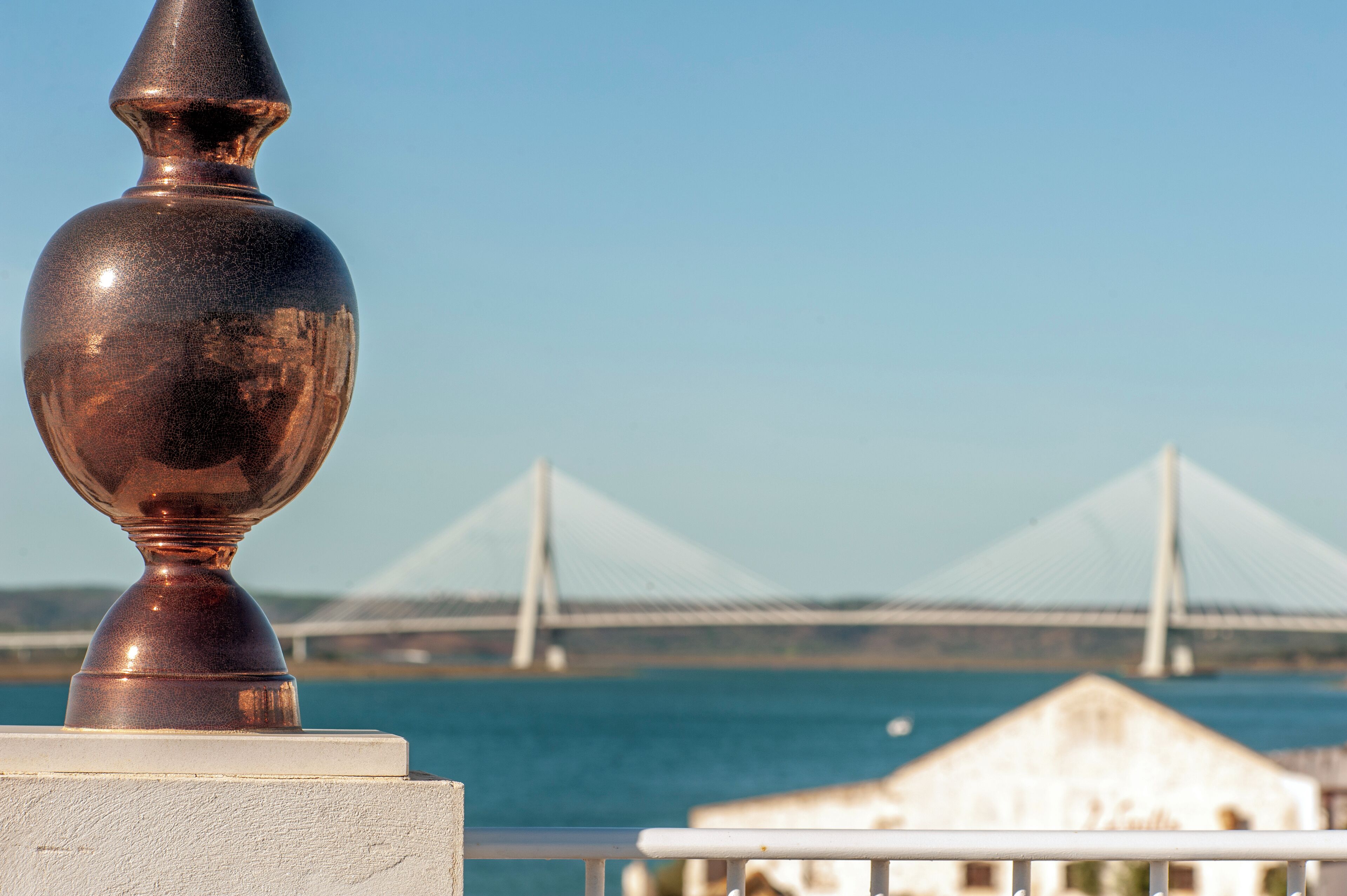 Vista de un puente de diseño moderno, un cuerpo de agua y un edificio al fondo.
