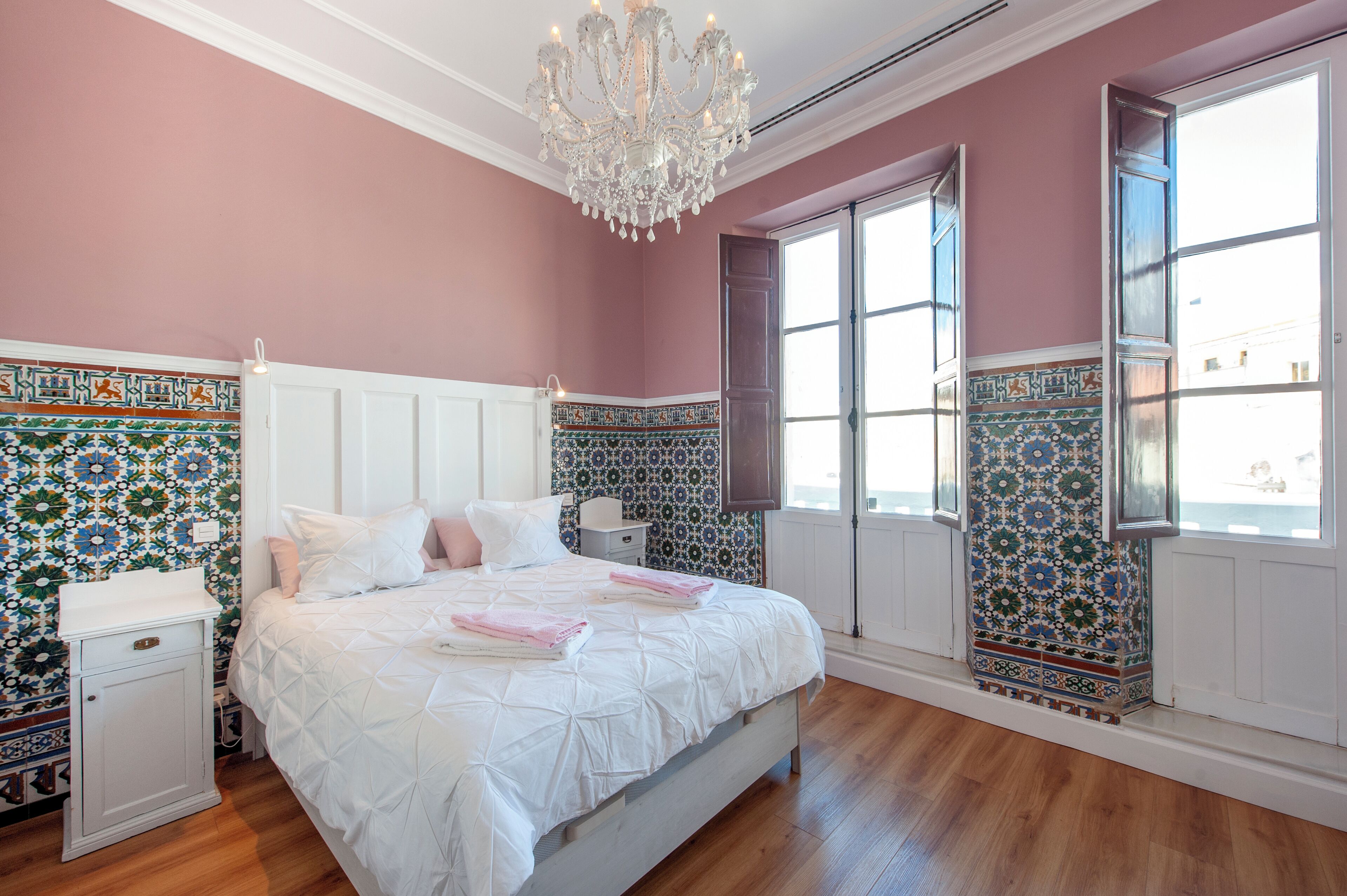 Une chambre à coucher avec un grand lit, une table de chevet, une commode et un lustre.