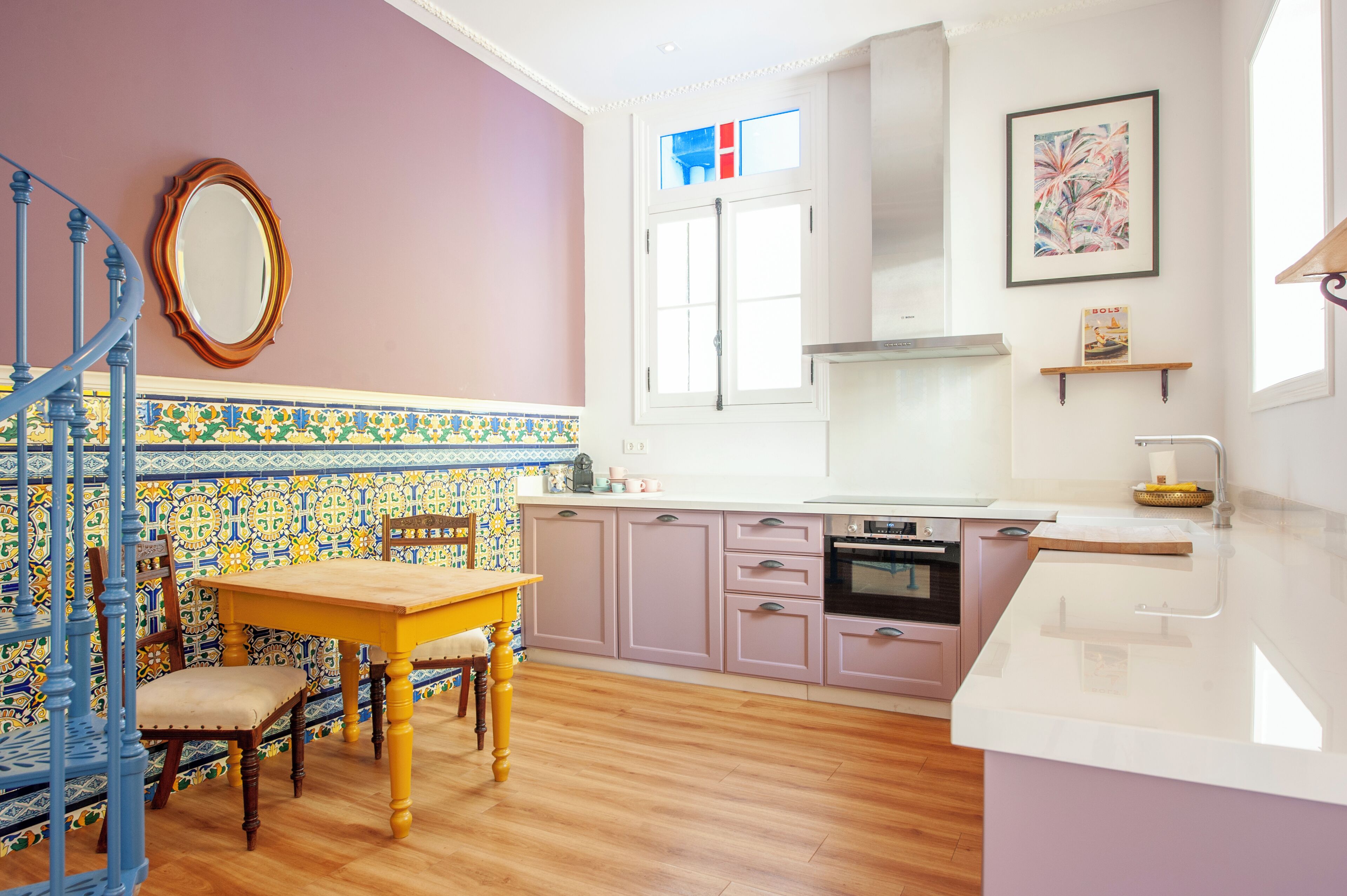A kitchen with a wooden dining table, chairs, and a tiled backsplash.