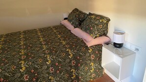 A bedroom with a floral bedspread, a pink pillow, and a bedside lamp. - Villa Arriba (Periana)