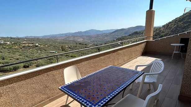 A terrace with a table and chairs, a view of the countryside, and a chimney. - Villa Arriba (Periana)