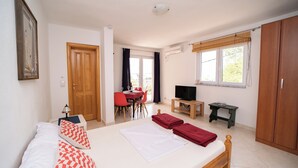 Ein Schlafzimmer mit Bett, Fernseher, Schreibtisch und Kleiderschrank.