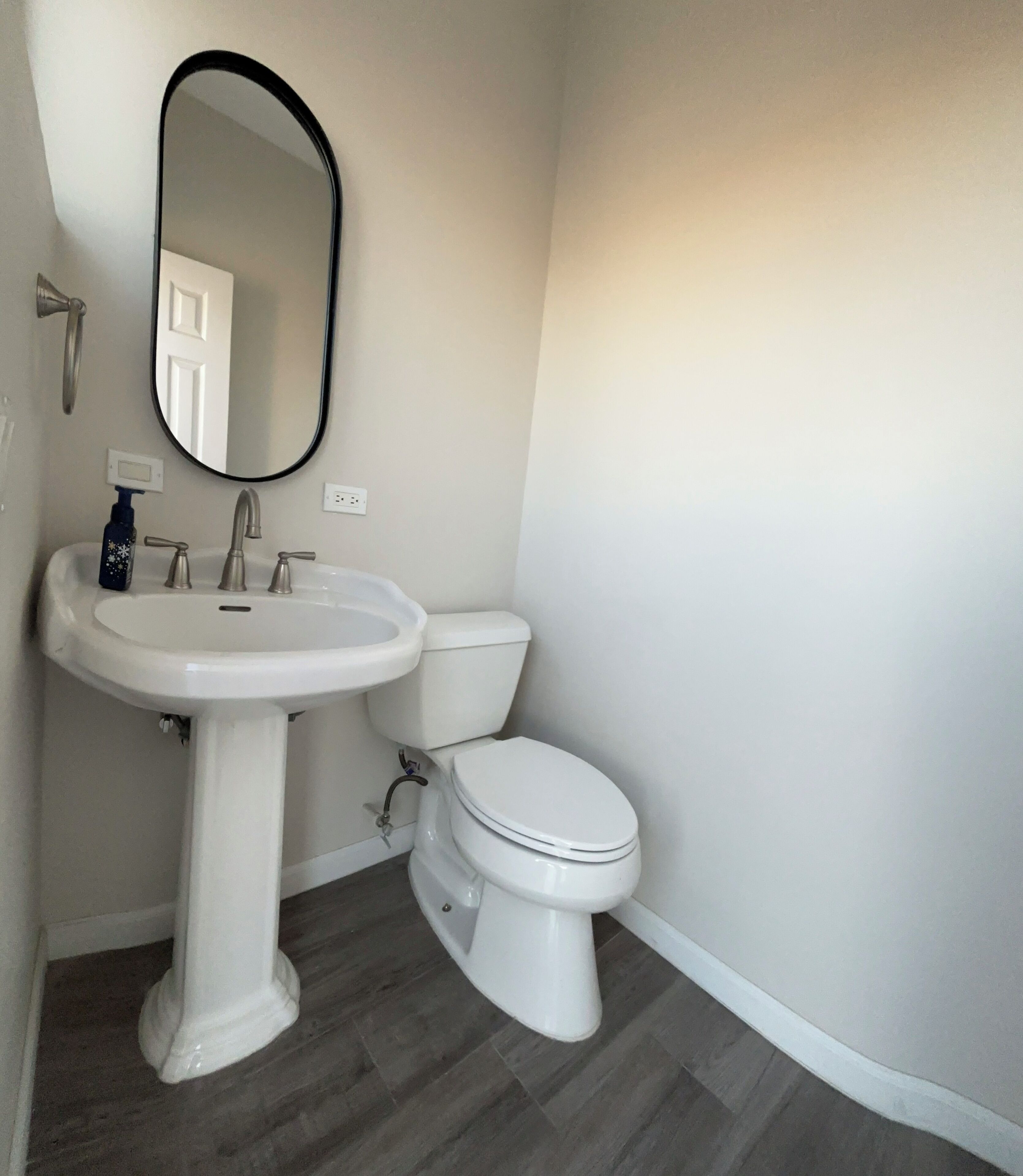 A bathroom with a pedestal sink, a toilet, and a mirror.