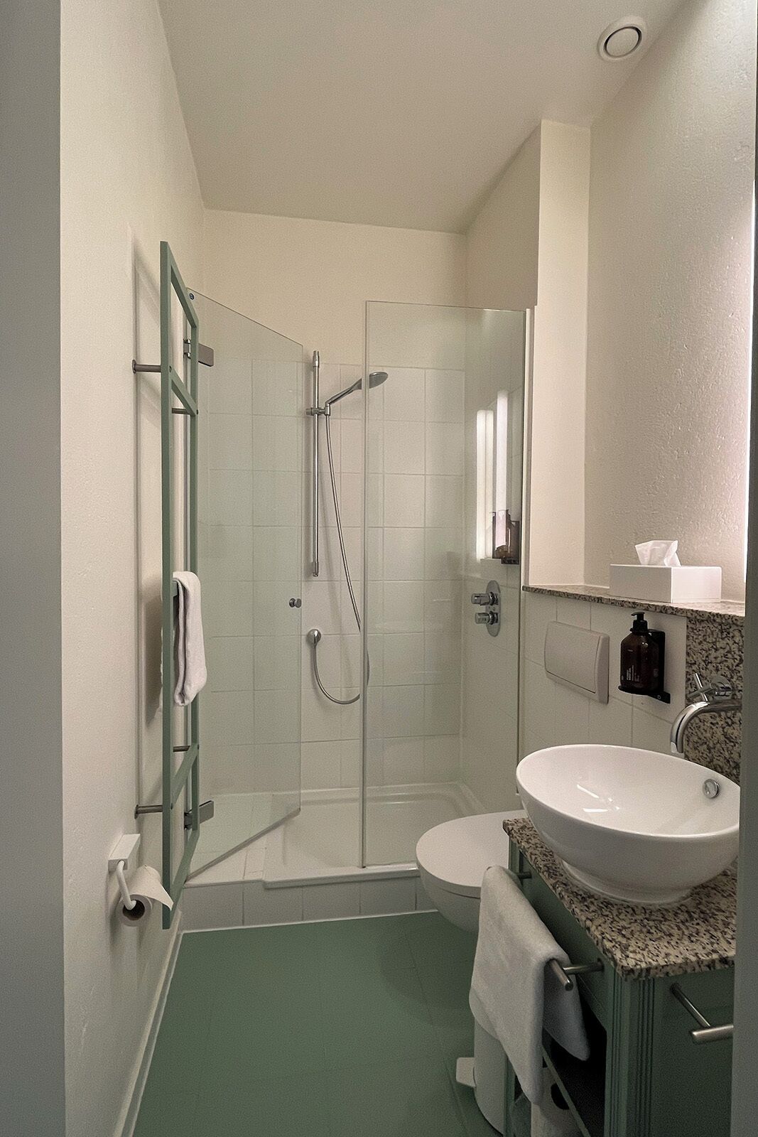 A bathroom with a glass-enclosed shower, a white sink, and a mirror above the sink.