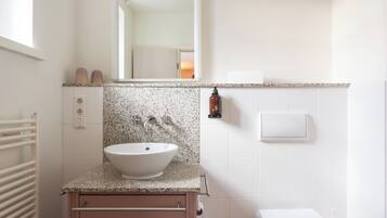 Un baño con lavamanos blanco, encimera de granito y váter blanco.