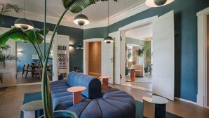 Een moderne woonkamer met een blauwe bank, ronde tafels en hangende hanglampen.