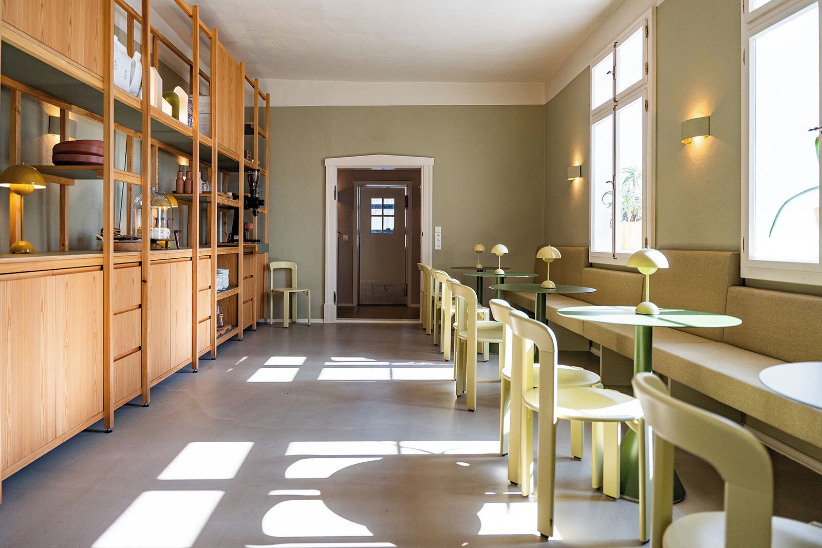 A library with wooden bookshelves, a central aisle, and tables with chairs.