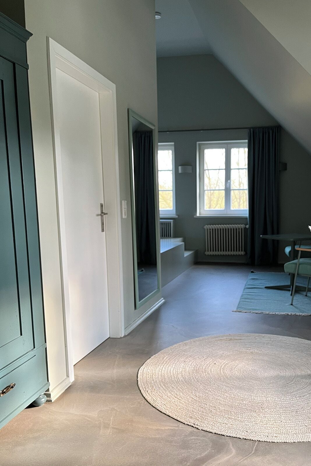 A spacious room with a large mirror, a radiator, and a view of the outdoors.