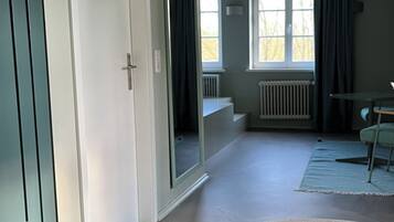 A spacious room with a large mirror, a radiator, and a view of the outdoors.