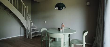 A dining area with a round table and six chairs, a staircase, and a pendant light.