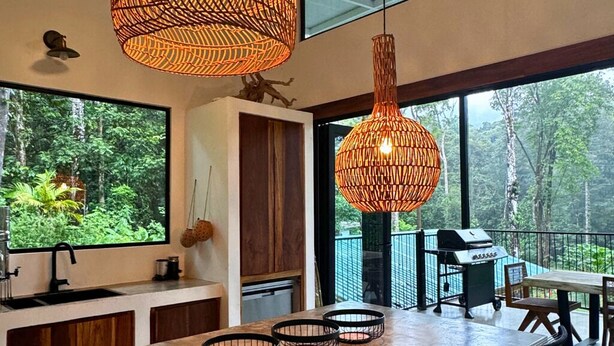 A modern kitchen with a large window, a dining area with a table and chairs, and a grill outside.