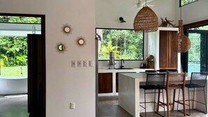 A modern kitchen with a large island, bar stools, and hanging wicker light fixtures.