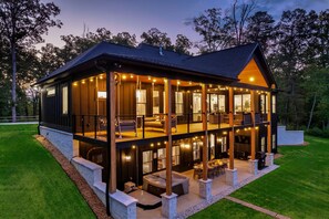 A two-story house with a covered patio, outdoor seating, and a hot tub.