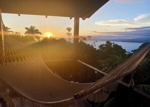 A hammock under a covered area with a view of the sunset over the ocean. - Mi Zaru beautiful sea view hotel (Quepos)