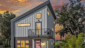 Una casa moderna de dos pisos con balcón, garaje y césped cuidado.