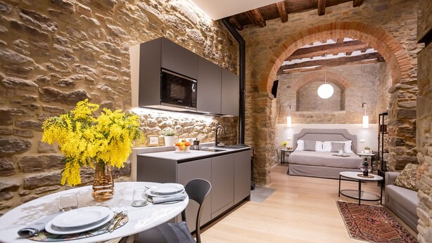 Un interior rústico de piedra con cocina, comedor y un dormitorio.