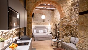 Una cocina moderna con horno integrado y barra desayunadora, un dormitorio acogedor con cama grande y mesita de noche, y una sala de estar con sofá y mesa de centro.
