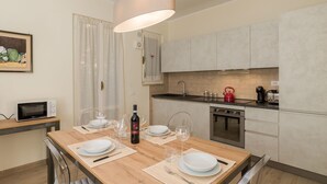 Una cocina moderna con una mesa de comedor de madera preparada para cuatro personas, un microondas, un hervidor de agua y una cafetera.