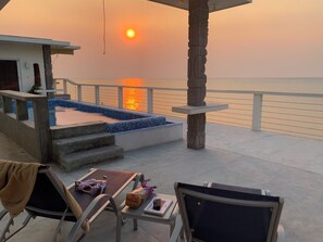 A terrace with a view of the sunset over the sea, a pool, and outdoor seating. - Trujillo Airport Beach Suites (Trujillo)