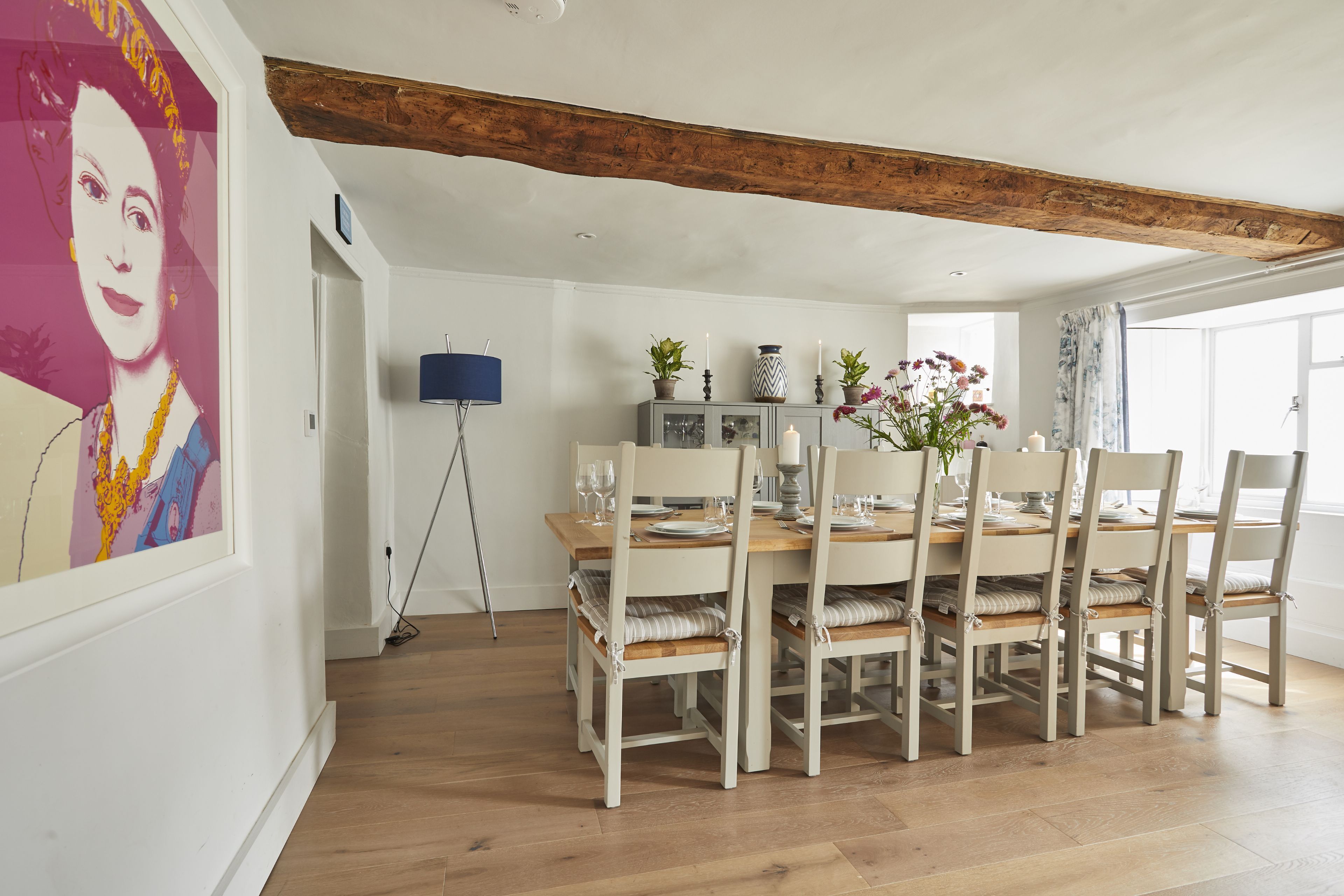 A dining area with a wooden table set for six, surrounded by six chairs with cushioned seats.