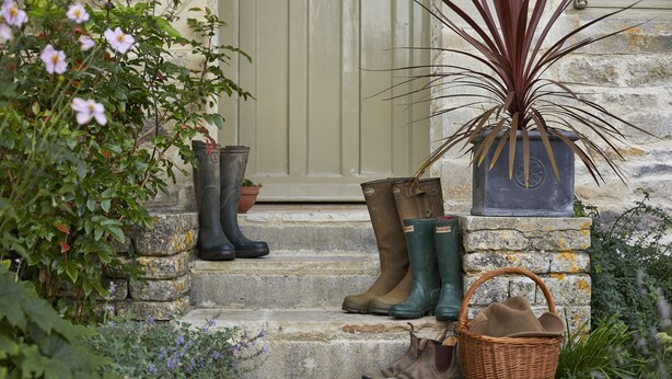 Un escalier en pierre menant à une porte, avec des bottes et un panier placés sur les marches.
