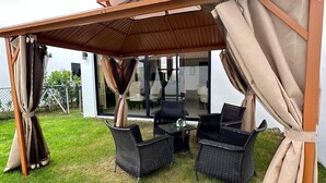 Een terras buiten met rieten meubilair en een pergola.