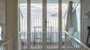 A spacious balcony with a view of snow-capped mountains, a table, and chairs. - Villa La Felice (pianello del lario)