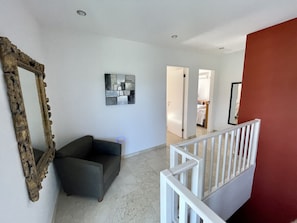 A modern living room with a grey sofa, a decorative mirror, and a contemporary art piece on the wall. - 2 Attached Villas for 26 Guests (Noord)