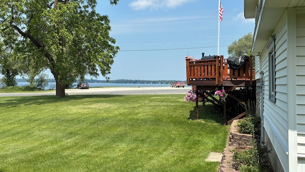 A house with a deck, a lawn, and a view of the water.