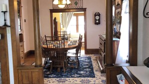 A dining area with a wooden table and chairs, a chandelier, and a patterned rug.