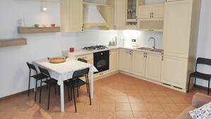 A compact kitchen with a dining table, chairs, a stove, and cabinets.