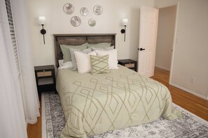 A neatly arranged bedroom with a bed, bedside tables, wall-mounted lamps, and a patterned rug.