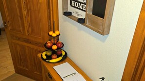 A wooden bench with a notepad, a fruit bowl, and a small window with a 'HOME' sign. - Luichart Lodge (Garve)