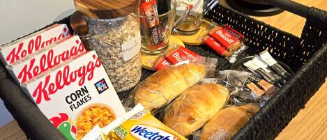 A tray with Kellogg's Corn Flakes, Weetabix, biscuits, bread, and a mug.