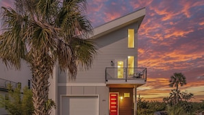 A modern two-story house with a balcony, a garage, and a well-maintained lawn.