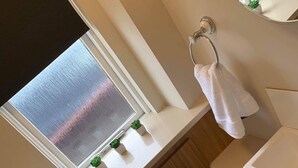 Ein modernes Badezimmer mit Fenster, Handtuchhalter, Waschbecken und Toilette.