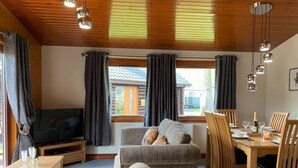 Ein gemütliches Wohnzimmer mit Fernseher, einer Couch und einem Essbereich mit Holzmöbeln.