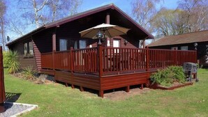 Eine Holzlaube mit umzäunter Terrasse, einer Veranda und einem kleinen Garten.