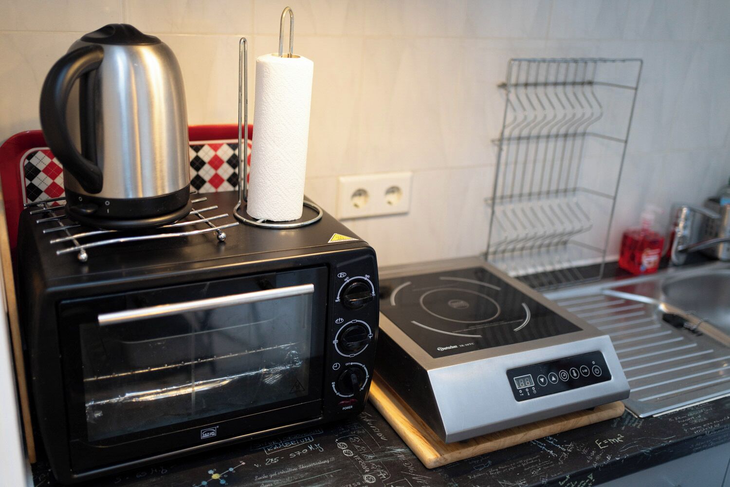 A kitchen with a toaster oven, a kettle, and a paper towel holder.