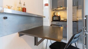 Eine kleine Küche mit eingebautem Regal, das Flaschen, eine Mikrowelle und einen Toaster beherbergt.