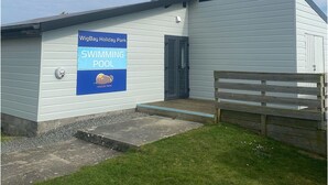 Ein Gebäude mit einem Schild, das einen Pool im WigBay Holiday Park bewirbt.