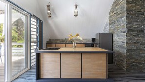 Eine moderne Küche mit einer Holzinsel, Steinwand und hängenden Pendelleuchten.