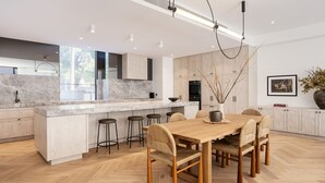 Una cocina moderna con una isla central, taburetes de bar y una mesa de comedor con sillas.