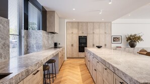 Una cocina moderna con encimeras de mármol, armarios de madera y un suelo con patrón de espiga.