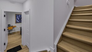 A modern interior with a wooden staircase, a desk with a computer, and a painting on the wall. - Luxury : Cozy| Modern| Clean| Spacious| easy Access to major routes in Calgary (Calgary)