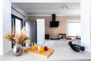 Una cocina moderna con refrigerador, microondas y tabla de madera con bebidas y una manzana.