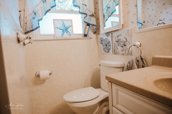 A bathroom with a toilet, sink, and decorative starfish artwork on the wall.